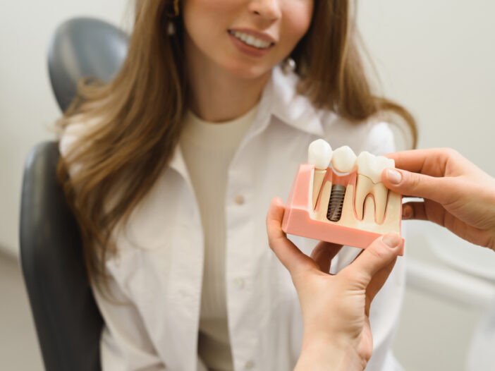 Dentist-showing-patient-model-of-dental-implant-for-tooth